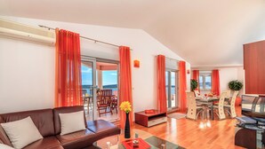Ein modernes Wohnzimmer mit einer braunen Ledersofa, einem Glastisch und einem Essbereich mit Holztisch und Stühlen.