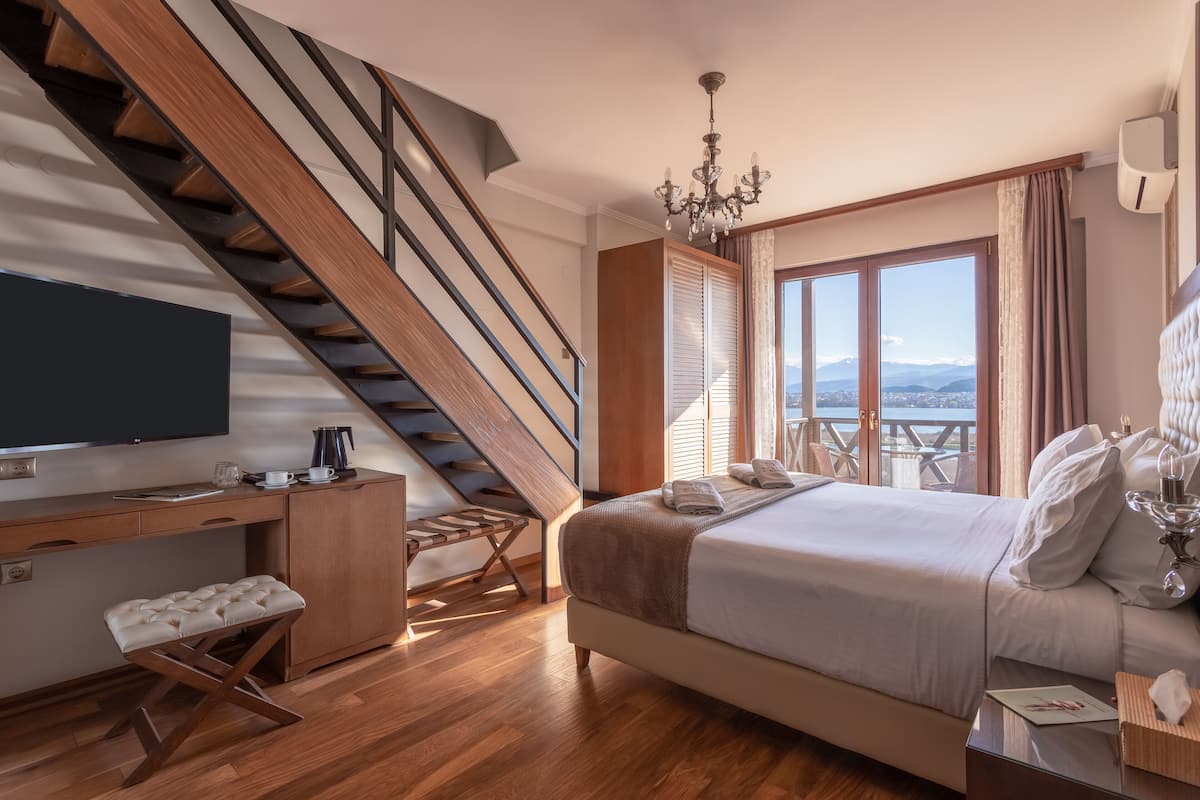 Ein Schlafzimmer mit einem großen Bett, einem Schreibtisch, einem Sessel, einem Fernseher und einer Treppe.
