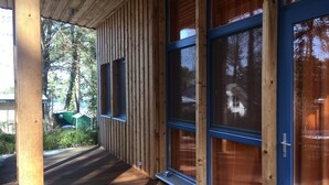 Une façade en bois, de grandes fenêtres et une véranda couverte.