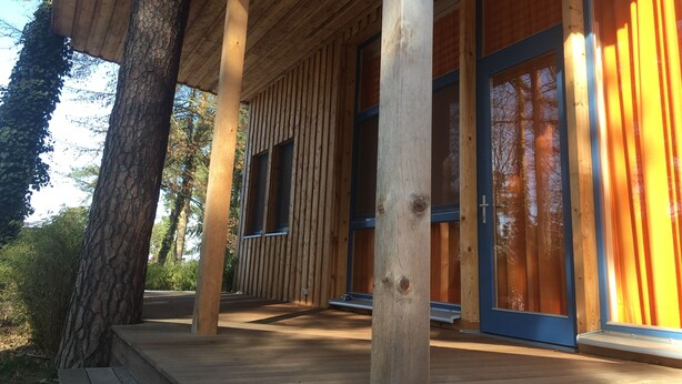 Une cabane en bois dotée de grandes fenêtres et d’un porche abrité.