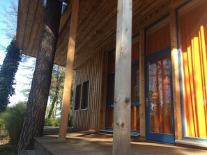Puinen mökki, jossa on suuret ikkunat ja katettu kuisti.