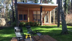 Une cabane moderne en bois, dotée d’une terrasse et de deux chaises longues.