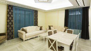 A spacious living room with a sofa set, a dining table, and a ceiling skylight. - Merada Suit Otel and Spa (Mezitli)