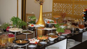 A buffet with various dishes and a golden vase with flowers. - Merada Suit Otel and Spa (Mezitli)