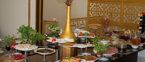 A buffet with various dishes and a golden vase with flowers.
