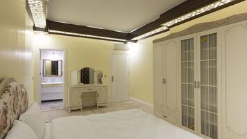 A bedroom with a bed, a dresser, a vanity, and a wardrobe.