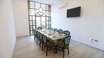 Un salón de conferencias con una larga mesa, sillas y una televisión en la pared.