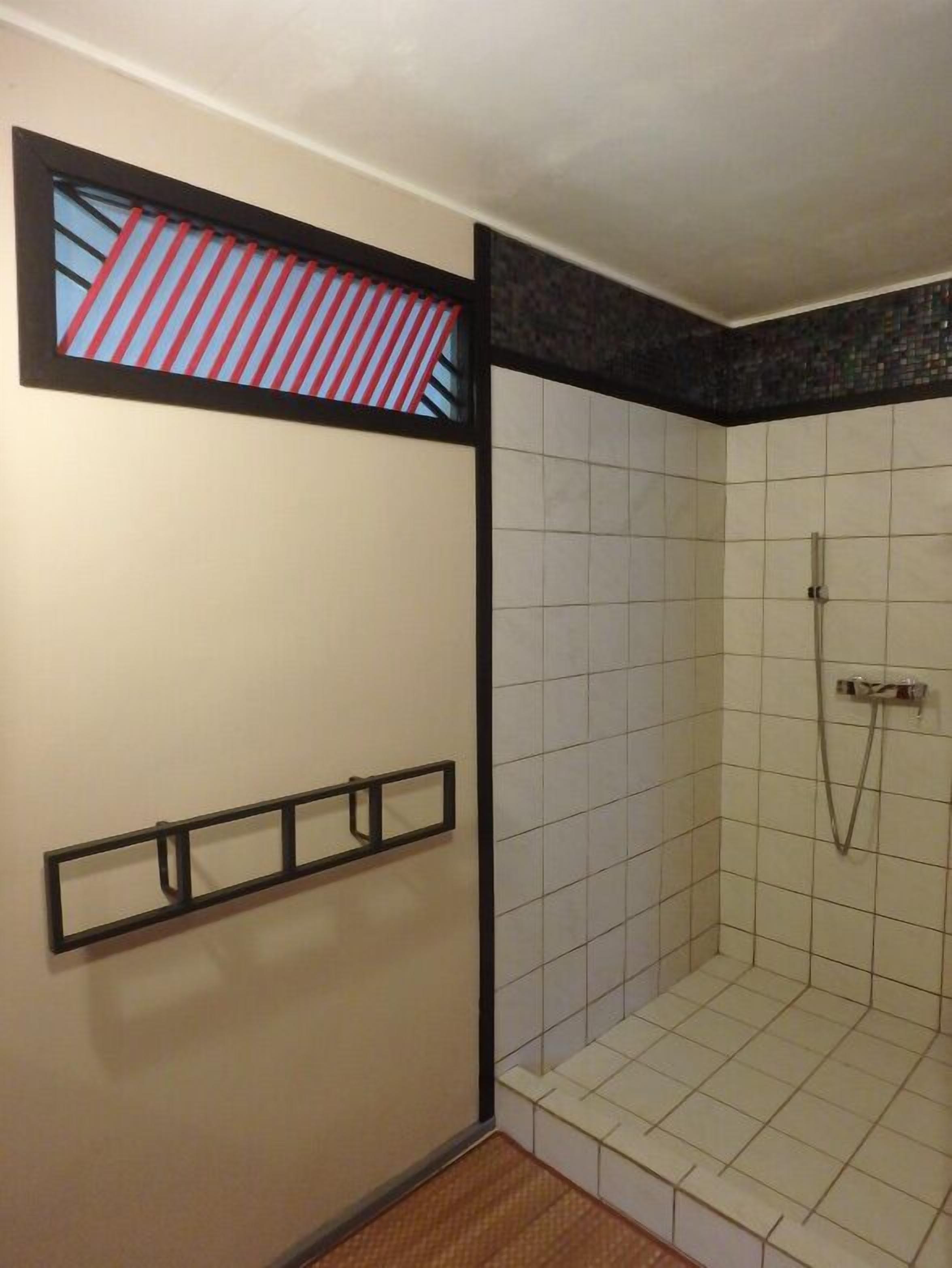 A small, tiled shower room with a window above the shower.