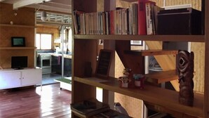 Ein Zimmer mit Holzboden, einem weißen Schrank mit Fernseher und einem Bücherregal voller Bücher und Dekoration.