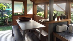 Eine moderne Küche mit Holztisch, einer Hängeleuchte und Blick auf den Garten durch große Fenster.