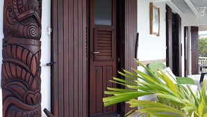 Une porte en bois ornée de sculptures complexes, une petite fenêtre et une plante verte au premier plan.