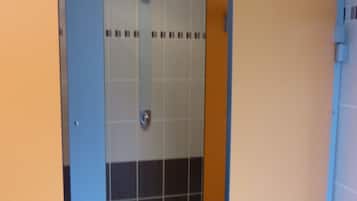 Een toiletruimte met blauwe en beige wanden, een betegeld doucheruimte en een deur met een handgreep.
