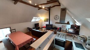 Una cuina compacta amb zona de menjador, fornell integrat i televisió.