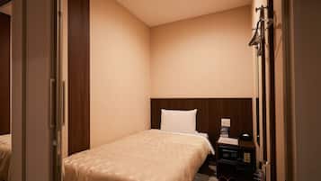 A hotel room with a bed, a wooden headboard, a nightstand, and a door leading to another room.