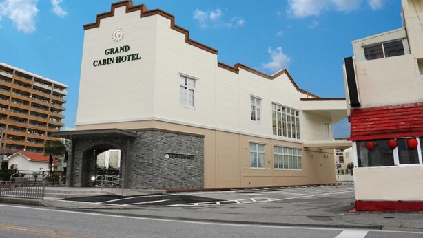 El exterior del Hotel Grand Cabin, con una entrada destacada, un arco de piedra y un cielo azul claro.
