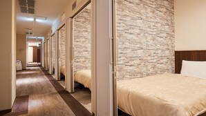 Habitación de hotel con pared de ladrillo, cabecera de madera y cama con colcha color beige.