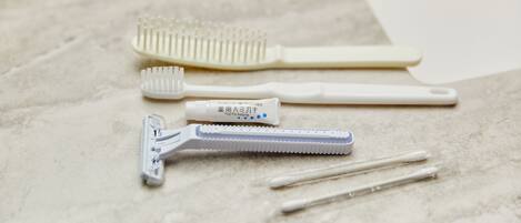 A set of personal care items including a toothbrush, a razor, and cotton swabs on a marble surface.