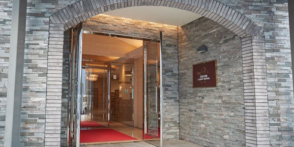 Fachada de hotel de piedra y puerta de cristal.