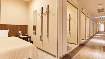 Habitación de hotel con cama, mesita de noche y espejo. Varias puertas dan acceso a otras habitaciones.