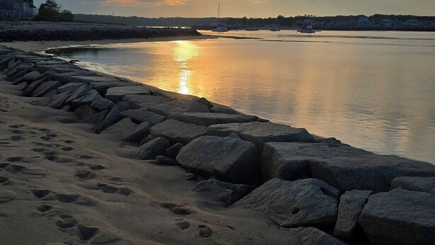 A beach with footprints in the sand, a rocky breakwater, and a sunset over the water. - Beachside Family Getaway! 3 Doors From Beach Access. Fantastic!!!! (Biddeford)