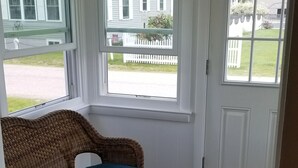 A room with a wicker sofa, wooden flooring, and a white door with windows. - Beachside Family Getaway! 3 Doors From Beach Access. Fantastic!!!! (Biddeford)