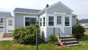 A two-story house with a front porch, a small garden, and a staircase leading to the entrance. - Beachside Family Getaway! 3 Doors From Beach Access. Fantastic!!!! (Biddeford)