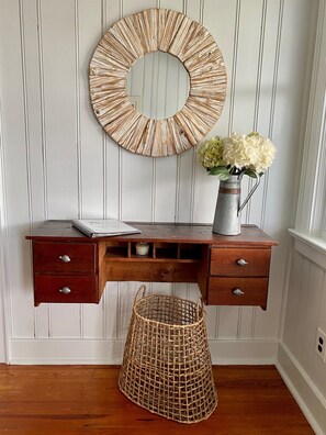 A wooden desk with drawers, a round mirror, a vase with flowers, and a wicker basket against a paneled wall. - Ocean views everywhere! / Beach access in front of house! /close to restaurants. (Isle of Palms)
