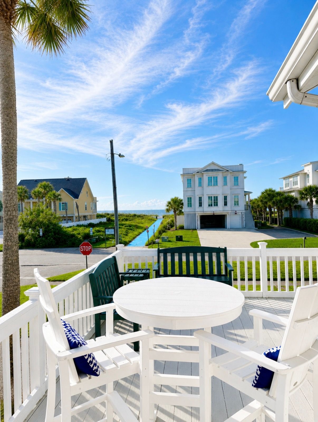 A white deck with outdoor furniture, a stop sign, and a view of a building with a blue sky.