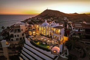 A resort with a pool, multiple dining areas, and a view of the sea at sunset. - Casa Rio de Luna: 7BR Ocean-View Villa with Pool, Rancho Cerro Colorado (Los Cabos)