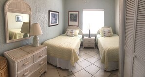 Ein Schlafzimmer mit zwei Betten, einem Schminktisch, einem Spiegel und gerahmten Bildern an der Wand.