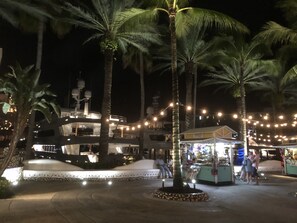 Ein Nachtblick auf ein Resort mit Palmen, einem Gebäude am Wasser und Lichterketten.