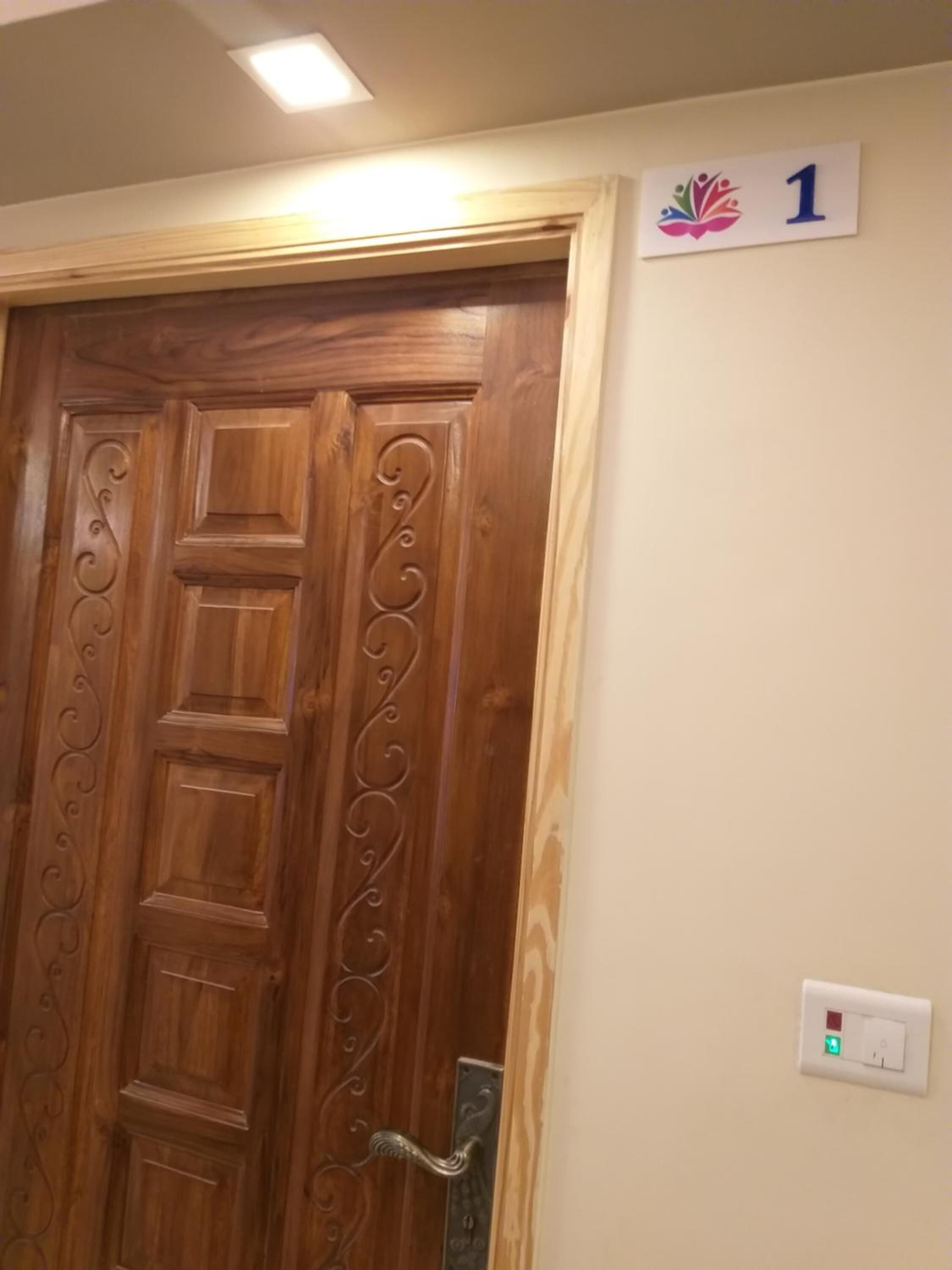 A wooden door with a decorative handle and a number sign above it.