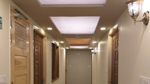 A hallway with wooden doors, a tiled floor, and recessed lighting. - Prem Niwas Boutique Hotel (Jaipur)
