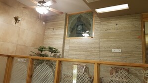 A room with a ceiling fan, a decorative window, and a wall-mounted air conditioner. - Prem Niwas Boutique Hotel (Jaipur)
