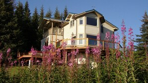 Ein zweistöckiges Haus mit Balkon, umgeben von einem Wald.
