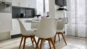 A modern kitchen with white cabinets, a built-in oven, and a dining area with white chairs and a table. - CONTEMPORARY APARTMENT NICE HYPER CENTER 2 MINUTES BEACHES (Nice)