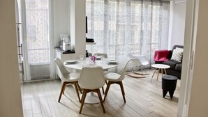 A modern dining area with a round table, white chairs, and a coffee machine. - CONTEMPORARY APARTMENT NICE HYPER CENTER 2 MINUTES BEACHES (Nice)