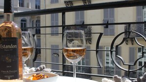 A table with a bottle of wine, glasses, and a bowl of snacks on a balcony with a view of buildings. - CONTEMPORARY APARTMENT NICE HYPER CENTER 2 MINUTES BEACHES (Nice)