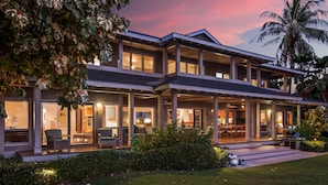 A two-story house with a covered porch, large windows, and a well-maintained lawn.