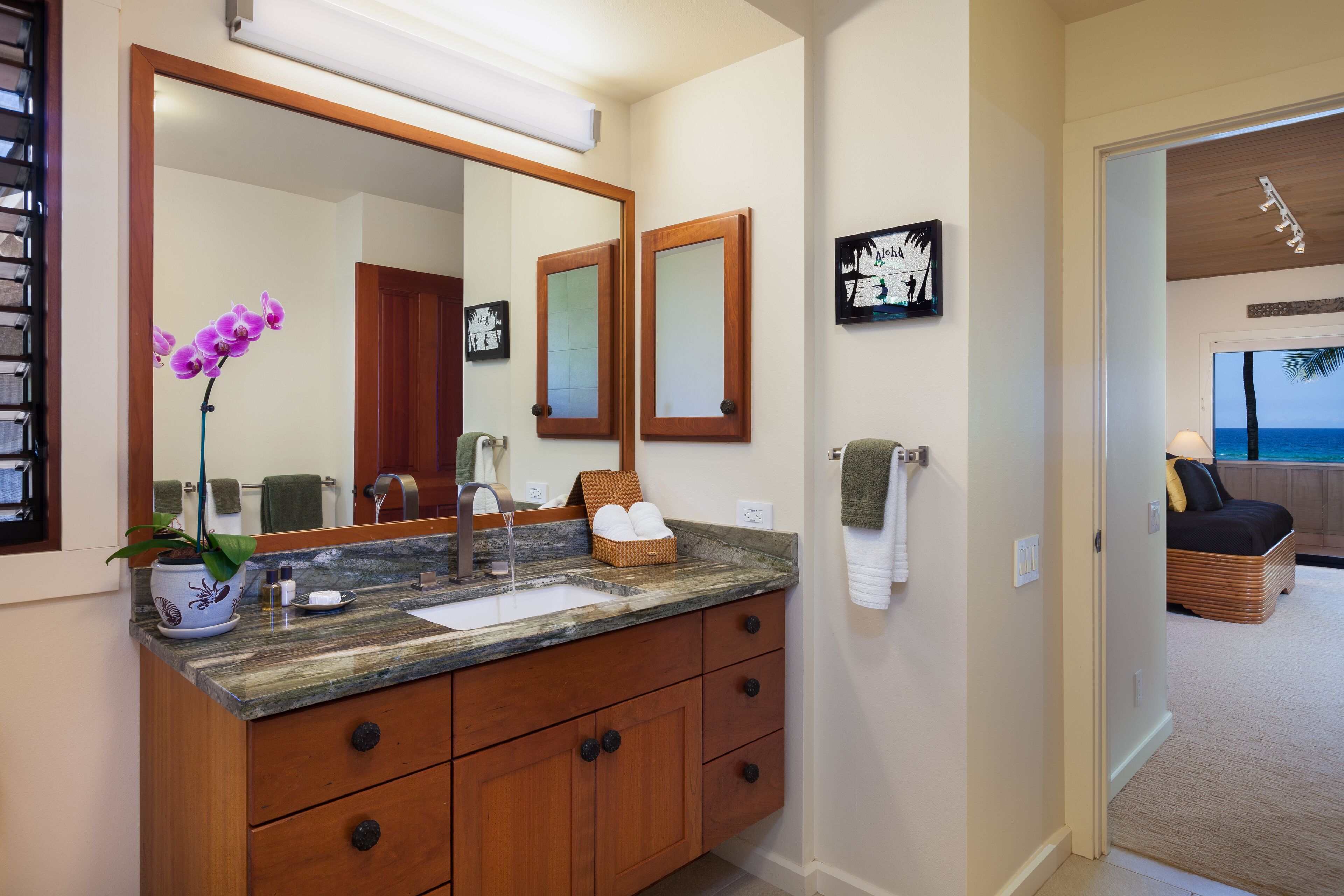 A bathroom with a marble sink, wooden vanity, and a large mirror.