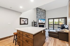 A modern kitchen with a stone accent wall, a fireplace, and a large island. - Frisco Gem • Mountain Views • Clubhouse w/ Pool + 4 Hot Tubs (Frisco)