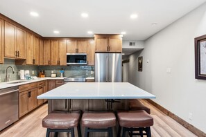 A modern kitchen with wooden cabinets, stainless steel appliances, and a central island with stools. - Frisco Gem • Mountain Views • Clubhouse w/ Pool + 4 Hot Tubs (Frisco)