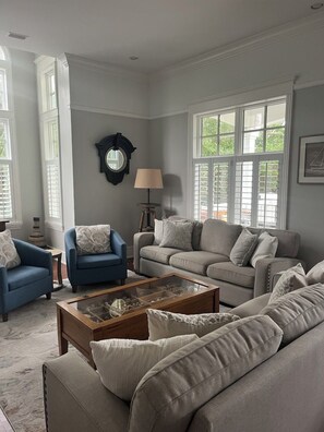 A living room with a beige sofa, a blue armchair, and a coffee table.