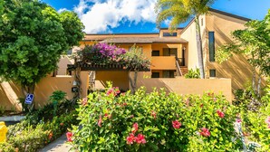 A multi-story building with balconies, surrounded by lush greenery and flowering plants. - Stunning Views, Walk to Beach! Spacious Ekahi 49F (Wailea)
