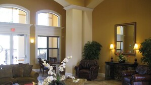 Eine Lobby mit einem braunen Sofa, einem Couchtisch und einer Topf-Orchidee. An der Wand befindet sich ein Spiegel und eine Tür mit einem Ausgangsschild.