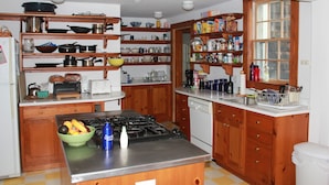Una cocina con armarios de madera, estufa a gas y diversos electrodomésticos.