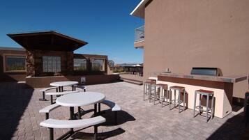 Un patio al aire libre con mesas de picnic y una zona de bar.