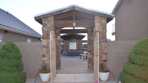 A covered patio area with stone walls and a metal roof, leading to a seating area with a table and chairs. - Tacit Shadow "Aviator", Private Bedroom at base of Brian Head Mountain, WiFi (Parowan)