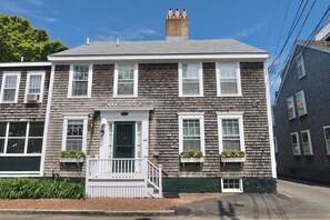 A two-story residential building with a front porch, a chimney, and a number "49" on the door. - Historic Sea Captains Home in Nantucket! Perfect for Large Groups and Families (Nantucket)