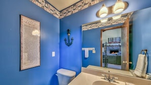 A bathroom with a blue wall, a white toilet, a sink with a mirror, and a framed sign on the wall. - Meadow Drive Home In Beautiful Lake Tahoe Nevada (Stateline)